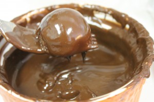 Dipping the truffle in melted chocolate.